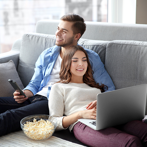 Couple watching TV and eating popcorn on couch