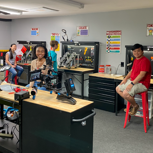 A group of students in a creative space smiling at the camera
