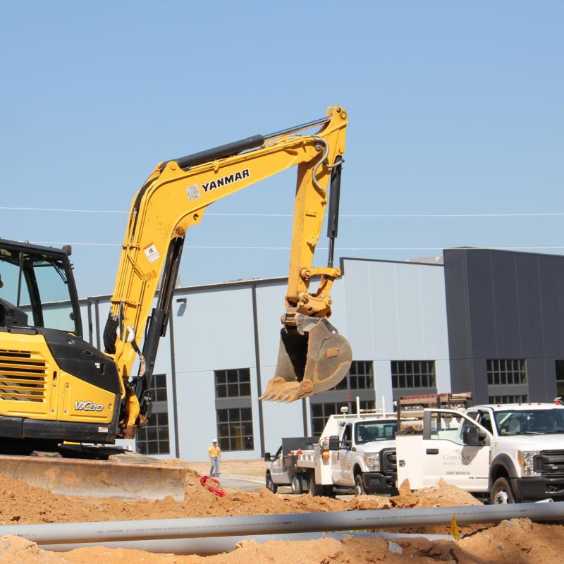 Bulldozer in front of a building with two Cobb EMC trucks