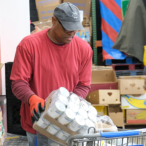 A man loading canned goods into a shopping cart