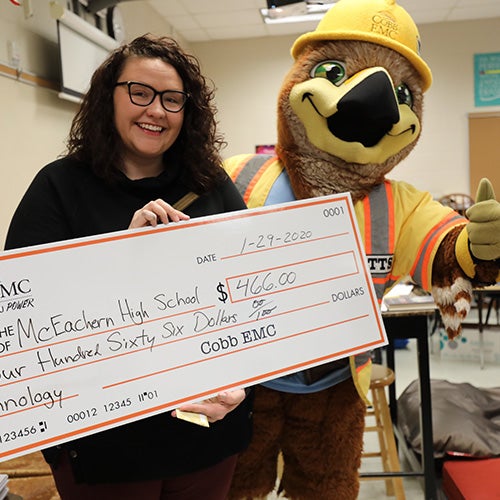 Mascot and teacher holding big check