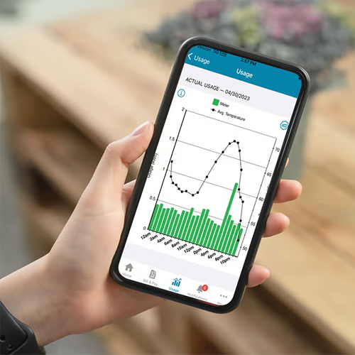 A hand holding a cell phone displaying an electricity usage graph